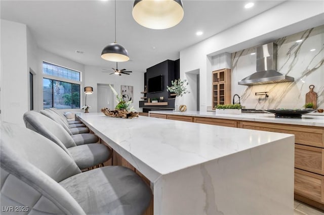 1350 Rossini St, Henderson, NV 89052 - kitchen with wall chimney range hood, a kitchen island, light stone countertops, backsplash, and a ceiling fan
