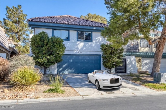 mediterranean / spanish house featuring an attached garage, driveway, a tiled roof, and stucco siding