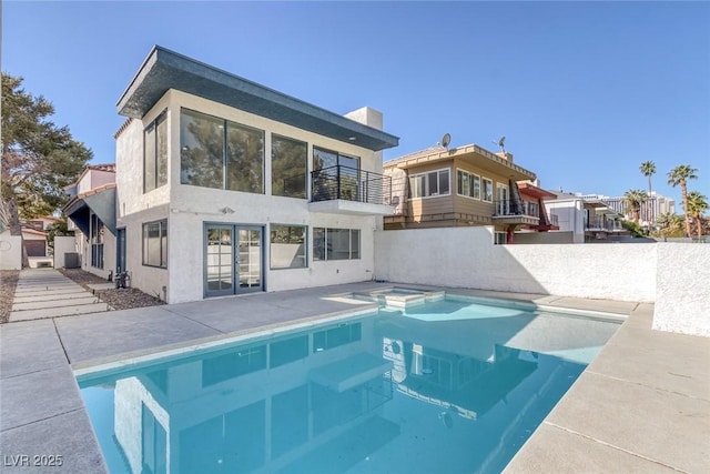 back of house with french doors, a fenced in pool, a patio area, a balcony, and stucco siding