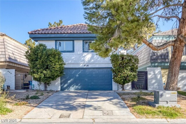view of front of house featuring concrete driveway, an attached garage, and a tile roof