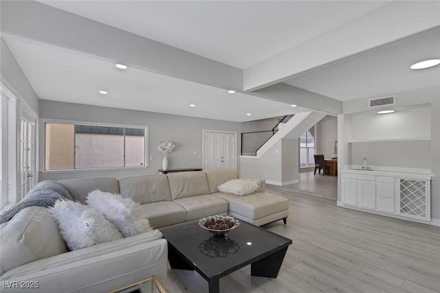 living room with recessed lighting, visible vents, baseboards, light wood-style flooring, and stairs