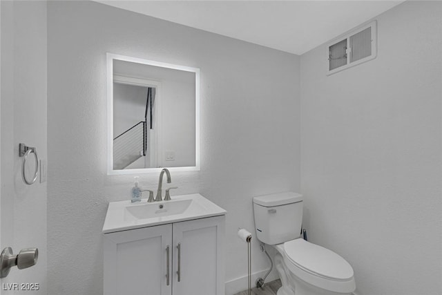 half bath featuring baseboards, vanity, and toilet