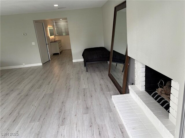 living room featuring baseboards, light wood finished floors, and a fireplace