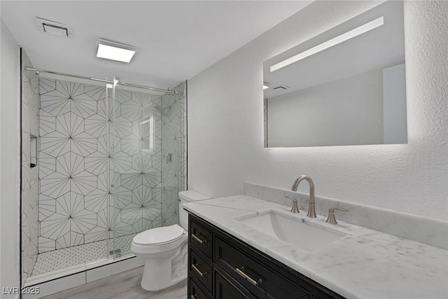 full bathroom featuring toilet, visible vents, wood finished floors, a shower stall, and vanity