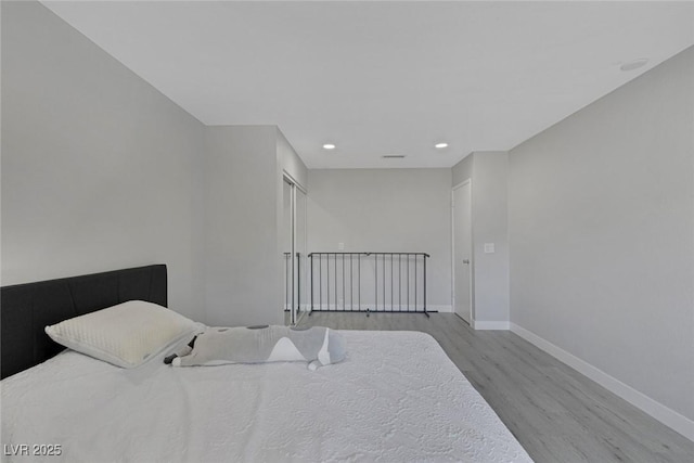 bedroom with baseboards, wood finished floors, and recessed lighting