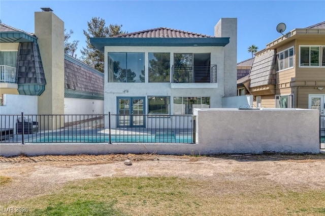 back of property with stucco siding, fence, and a fenced in pool