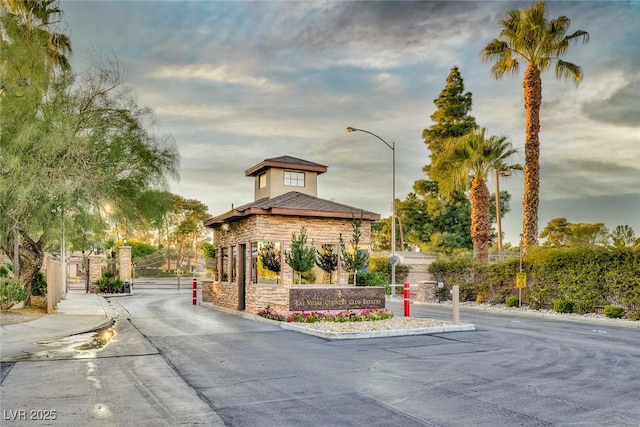 view of street featuring street lights, a gated entry, curbs, and a gate