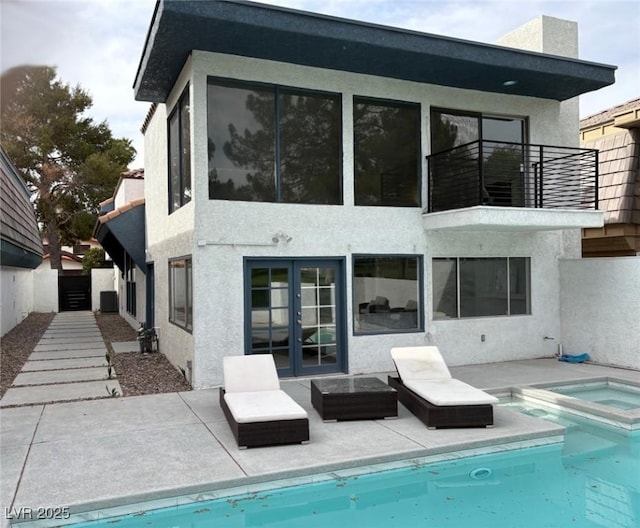 back of property featuring french doors, a patio, an in ground hot tub, and stucco siding