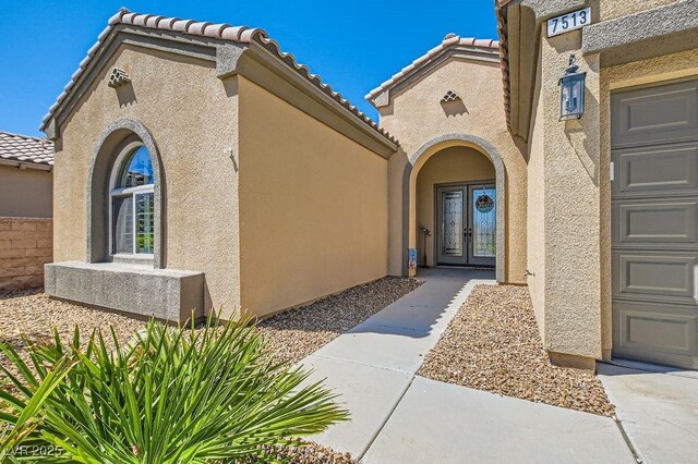 7513 Java Sparrow St, North Las Vegas, NV 89084 - property entrance with stucco siding, a tiled roof, and french doors