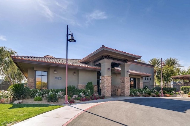 7513 Java Sparrow St, North Las Vegas, NV 89084 - view of front of home with stone siding, a tiled roof, stucco siding, and fence