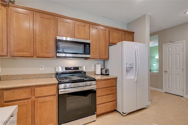 kitchen with brown cabinetry, stainless steel appliances, light countertops, and light tile patterned floors