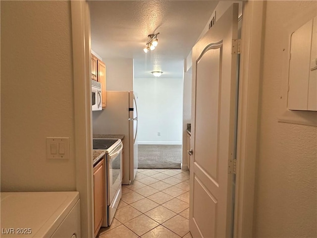 5055 W Hacienda Ave Unit 1095, Las Vegas, NV 89118 - kitchen with baseboards, white appliances, a textured ceiling, and light tile patterned floors