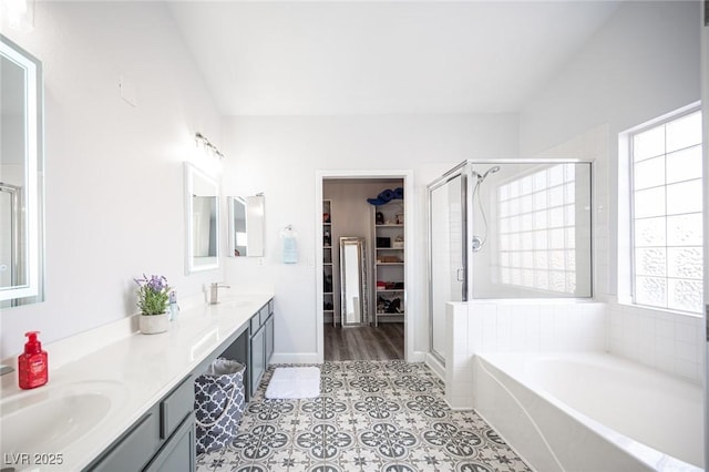 full bath with a bath, a sink, a spacious closet, and a stall shower