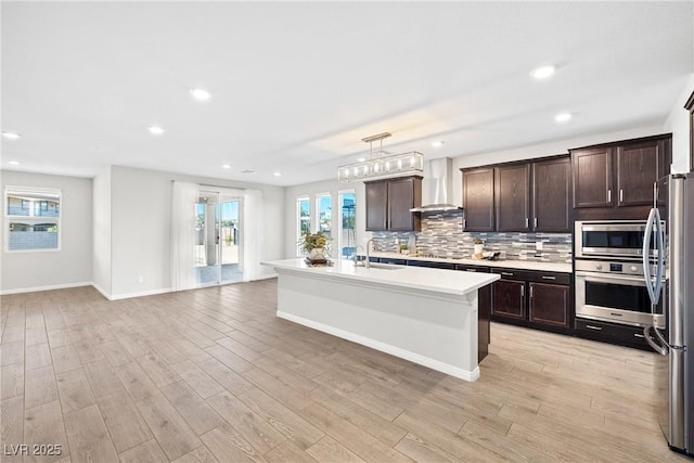 1512 Sagefield Way, Logandale, NV 89021 - kitchen with stainless steel appliances, wall chimney range hood, dark brown cabinets, light countertops, and tasteful backsplash