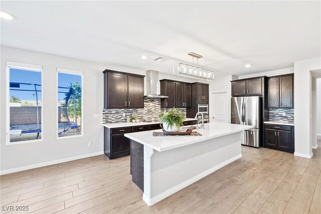 1512 Sagefield Way, Logandale, NV 89021 - kitchen with appliances with stainless steel finishes, wall chimney exhaust hood, light wood-style floors, light countertops, and backsplash