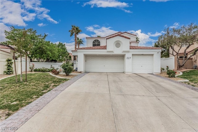 mediterranean / spanish-style house with stucco siding, a tile roof, driveway, and a front lawn