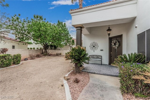 property entrance with stucco siding and fence