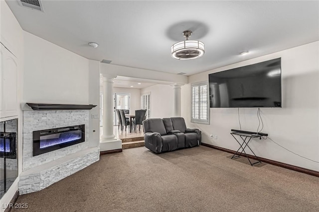 carpeted living room featuring a fireplace, visible vents, baseboards, and decorative columns