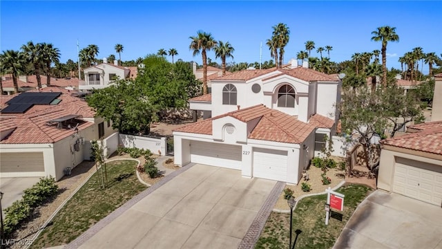 mediterranean / spanish-style house with stucco siding, a tiled roof, a garage, and concrete driveway
