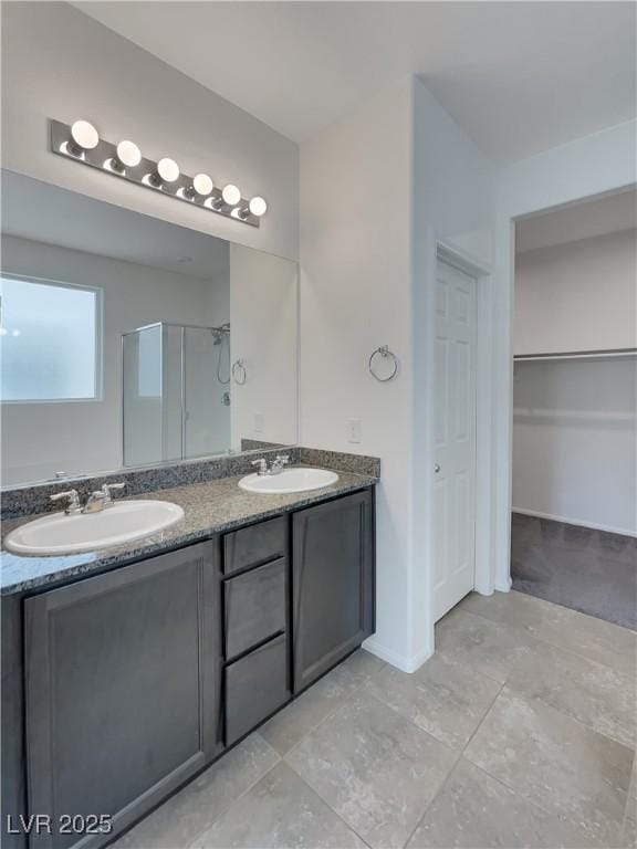 bathroom featuring a shower stall, double vanity, tile patterned floors, and a sink