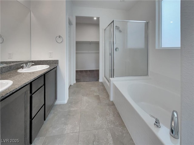 bathroom with a shower stall, a bath, a sink, and a spacious closet