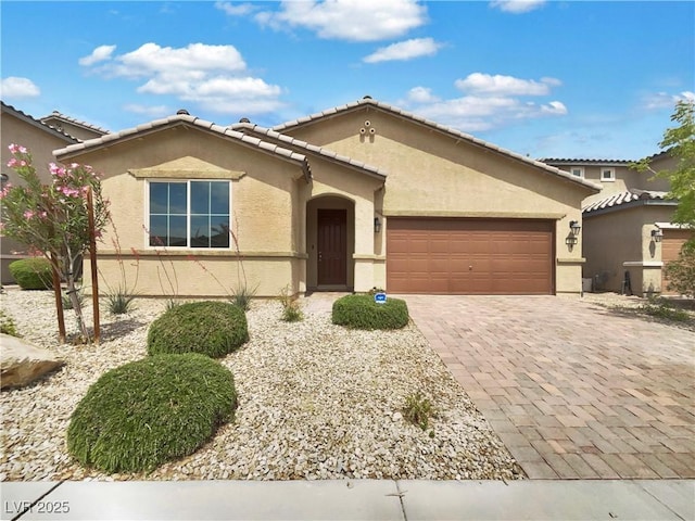 ranch-style house with an attached garage, stucco siding, and decorative driveway