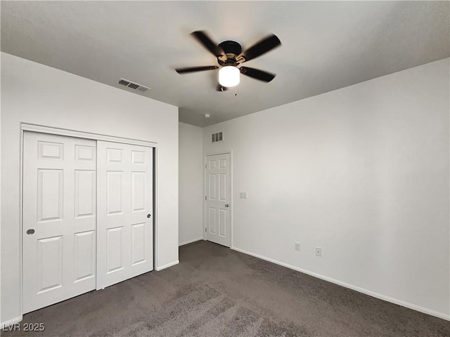 unfurnished bedroom with baseboards, dark colored carpet, visible vents, and a closet