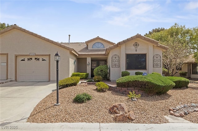 view of front of property featuring concrete driveway, a tile roof, stucco siding, and a garage