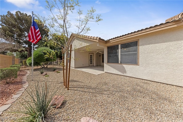 rear view of house featuring a tile roof, a patio, stucco siding, and fence