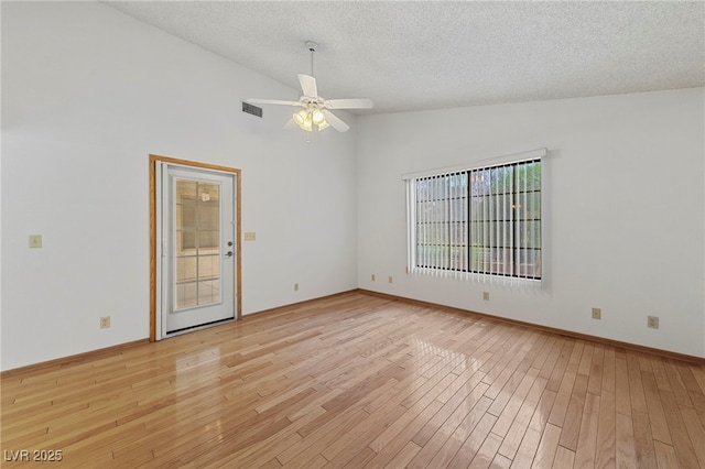 empty room with a textured ceiling, light wood-type flooring, visible vents, ceiling fan, and high vaulted ceiling