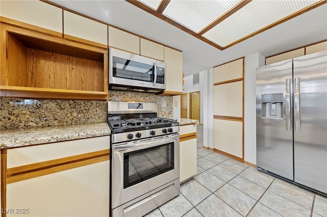kitchen with light stone counters, tasteful backsplash, light tile patterned floors, stainless steel appliances, and visible vents