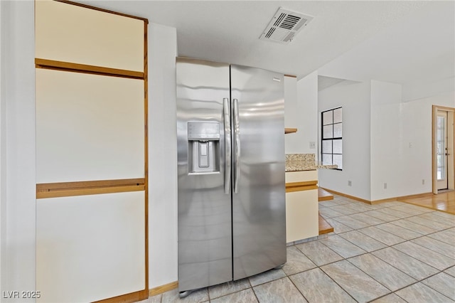 kitchen with light tile patterned floors, stainless steel fridge with ice dispenser, light countertops, baseboards, and visible vents