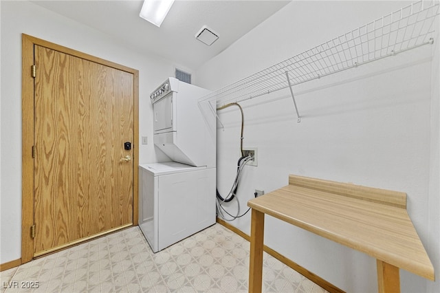 laundry area with baseboards, visible vents, stacked washer / dryer, light floors, and laundry area