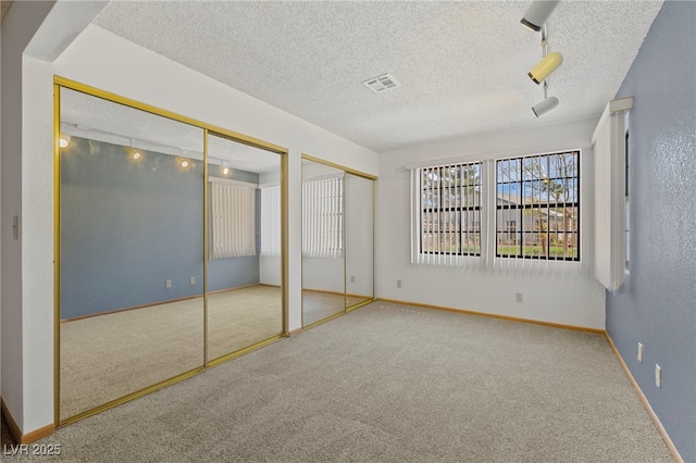 unfurnished bedroom with baseboards, two closets, visible vents, and carpet floors