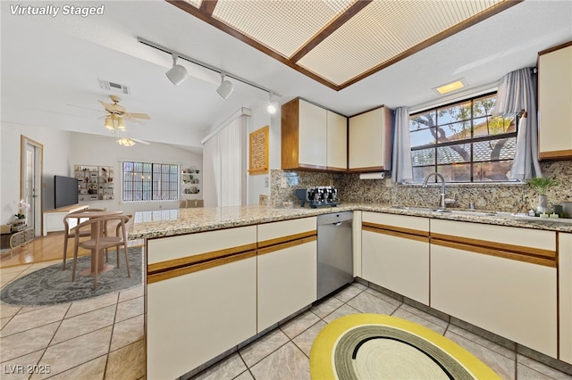 kitchen featuring dishwasher, backsplash, a sink, and visible vents