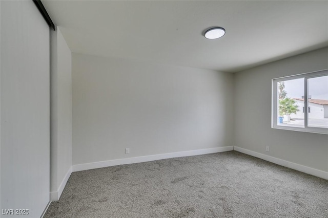 spare room with baseboards and carpet flooring