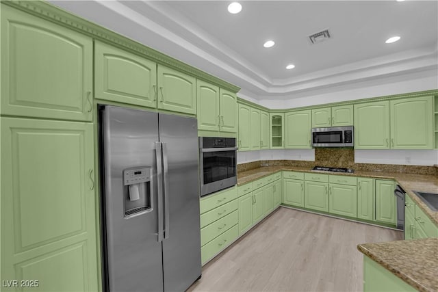 4722 Blue Mesa Way, Las Vegas, NV 89129 - kitchen featuring appliances with stainless steel finishes, green cabinets, light wood-style flooring, a tray ceiling, and backsplash