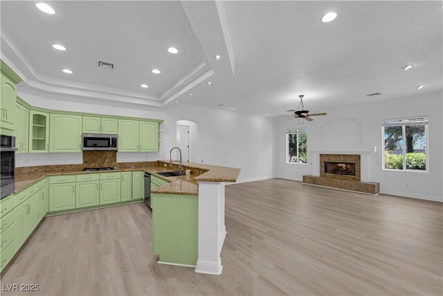 4722 Blue Mesa Way, Las Vegas, NV 89129 - kitchen featuring a peninsula, appliances with stainless steel finishes, a sink, a tiled fireplace, and green cabinetry