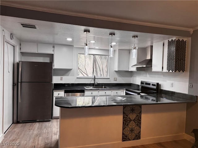 3275 Arville St Unit C, Las Vegas, NV 89102 - kitchen with stainless steel appliances, wall chimney range hood, a sink, a peninsula, and light wood-style flooring
