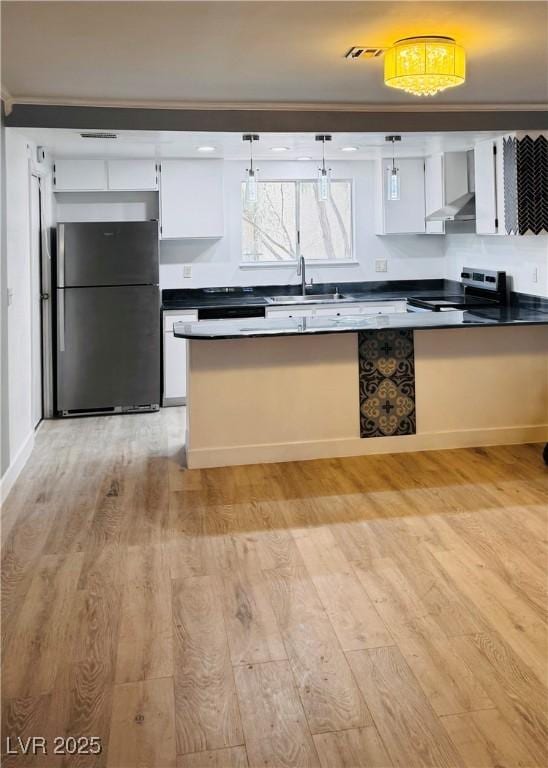 3275 Arville St Unit C, Las Vegas, NV 89102 - kitchen with freestanding refrigerator, stainless steel electric range oven, a sink, light wood-style floors, and white cabinetry