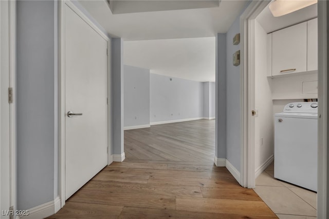hallway with washer / dryer, baseboards, and light wood-style flooring
