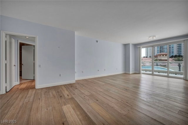 empty room with baseboards and light wood-style floors