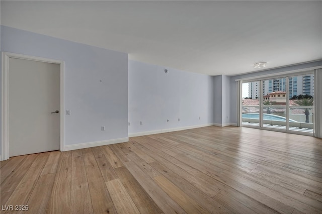 spare room with light wood-style floors and baseboards