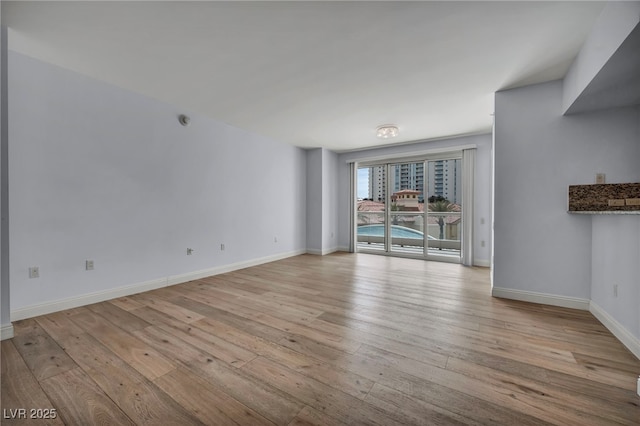 unfurnished living room featuring baseboards and light wood finished floors