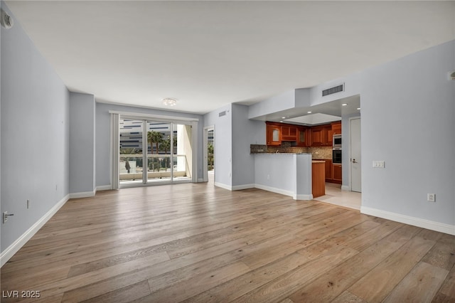 unfurnished living room featuring light wood-style floors, baseboards, and visible vents