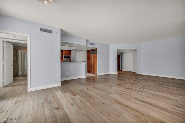unfurnished living room featuring baseboards, visible vents, and light wood-style flooring