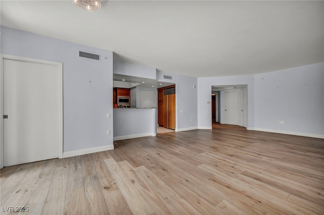 unfurnished living room with baseboards, visible vents, and light wood-style flooring