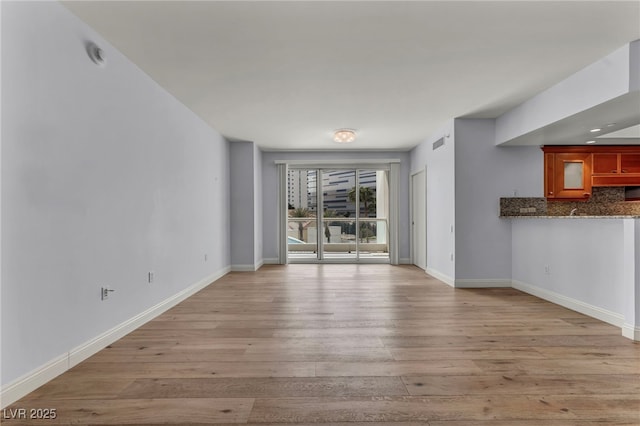 unfurnished living room featuring baseboards, light wood-style flooring, and visible vents
