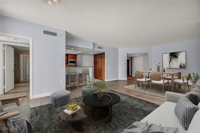 living room featuring baseboards, light wood-style flooring, and visible vents