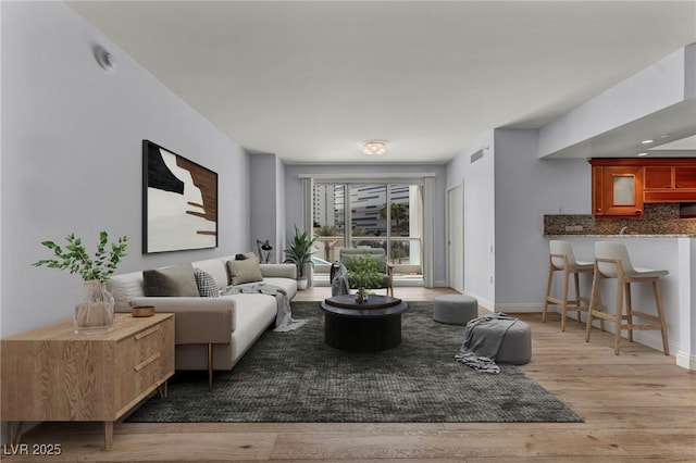 living room featuring baseboards, visible vents, and light wood-style flooring